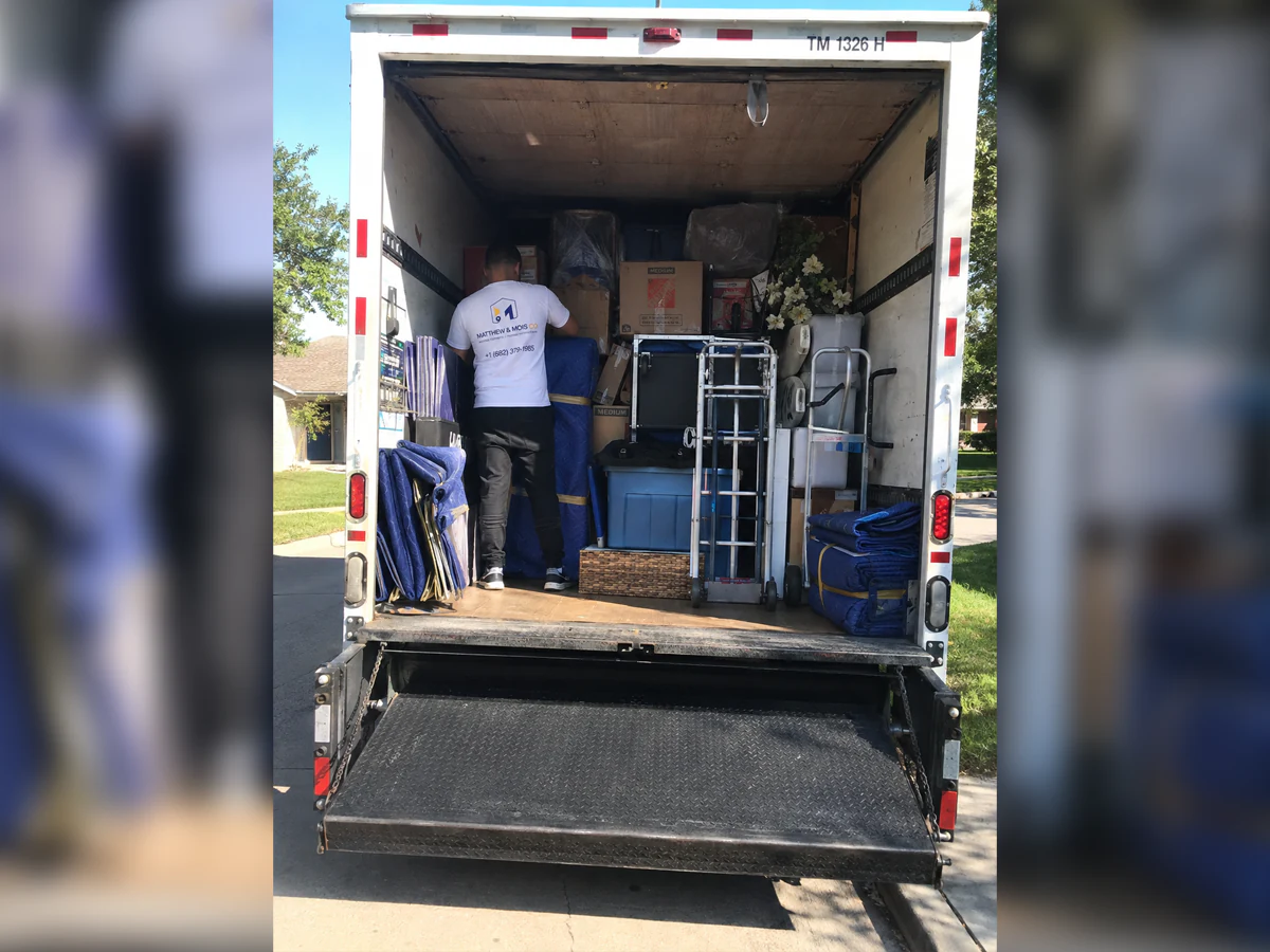 Matthew & Mois mover loading a truck packed with wrapped furniture, boxes and dollies