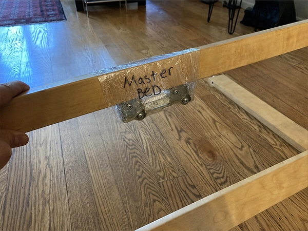 A bed rail with its hardware taped to it and labeled Master BED