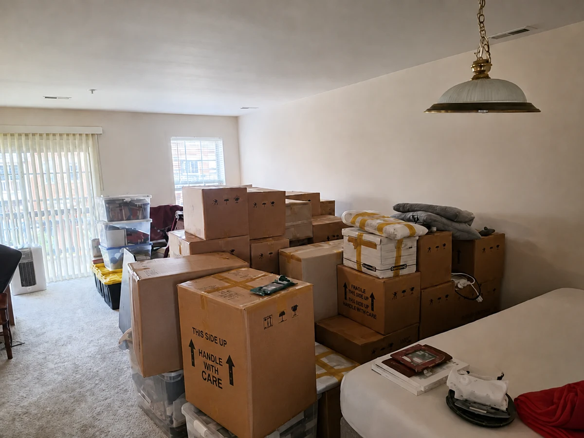 A cleared room holding rows of packed cartons, several marked This Side Up and Handle With Care