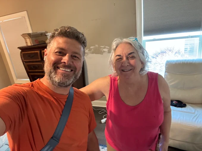 A Matthew and Mois crew member taking a selfie with a smiling customer in her living room